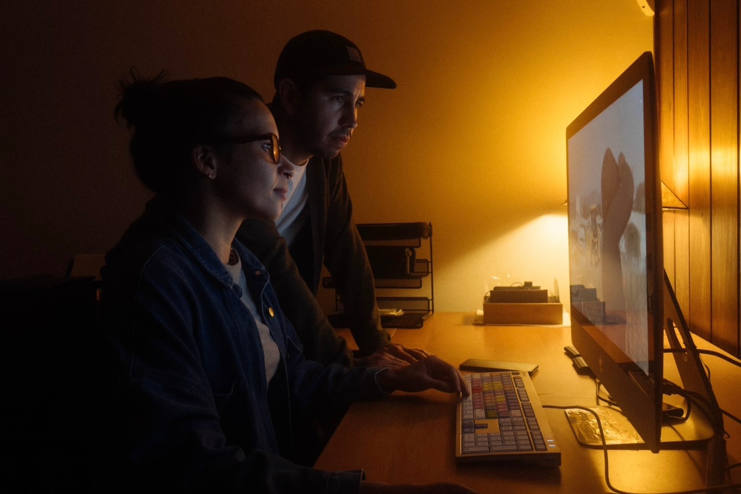 Filmmakers Estevan Padilla and Caron Creighton sit in front of a computer reviewing footage.